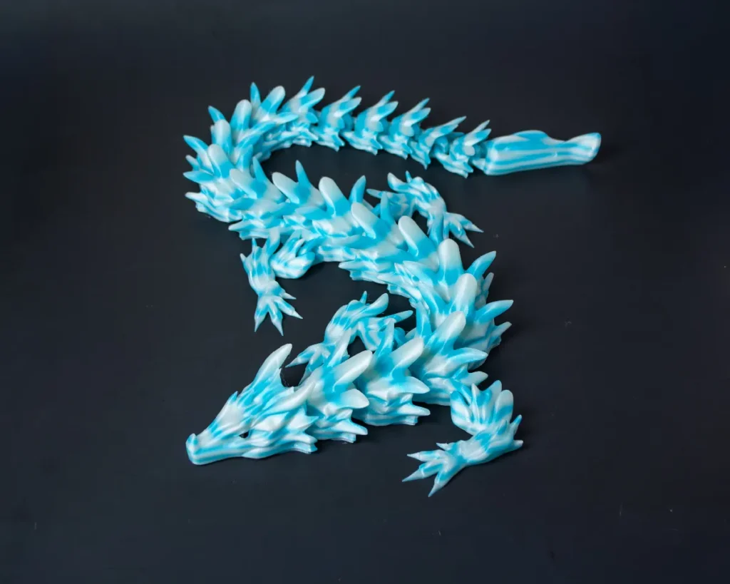 ForgeFi Articulated Dragon, a fully articulated print-in-place dragon with layered scales and spined back, shown coiled on a dark surface